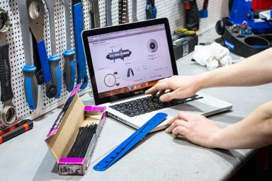 Un homme utilise un ordinateur portable sur un bureau d'atelier avec des outils en arrière-plan.